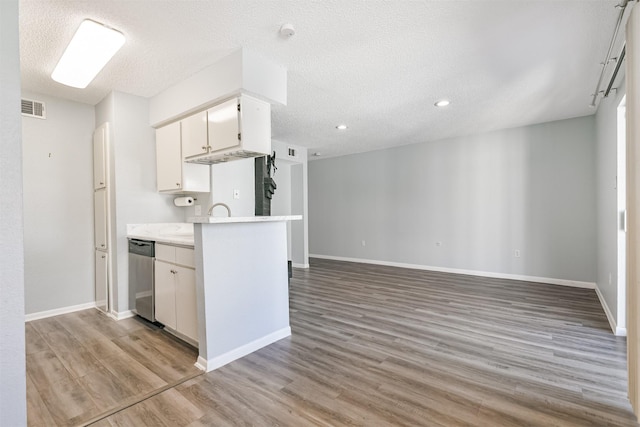 kitchen featuring kitchen peninsula, stainless steel dishwasher, a textured ceiling, white cabinets, and light hardwood / wood-style floors