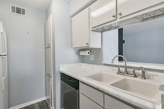 kitchen with white refrigerator, sink, stainless steel dishwasher, a textured ceiling, and white cabinetry