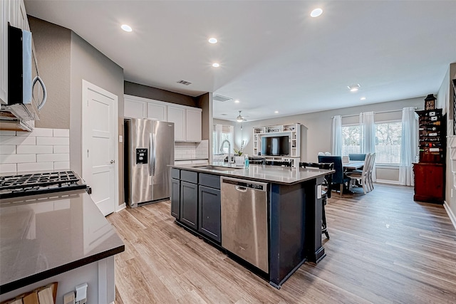 kitchen with sink, white cabinets, tasteful backsplash, a kitchen island with sink, and appliances with stainless steel finishes