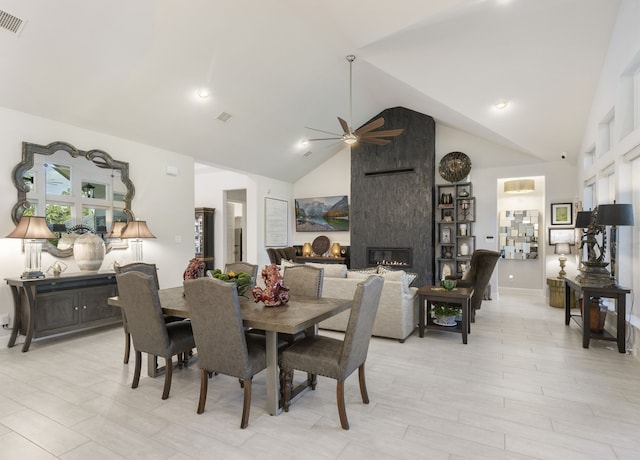 dining area featuring ceiling fan, lofted ceiling, a fireplace, and light hardwood / wood-style flooring