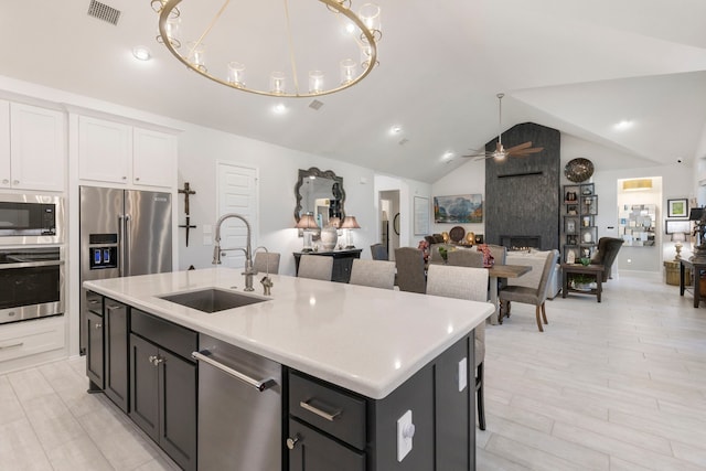 kitchen featuring sink, a kitchen island with sink, white cabinets, ceiling fan with notable chandelier, and appliances with stainless steel finishes