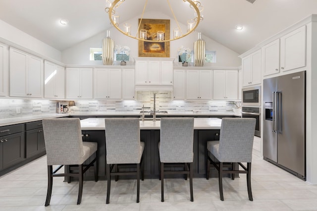 kitchen featuring an island with sink, white cabinets, stainless steel appliances, and lofted ceiling