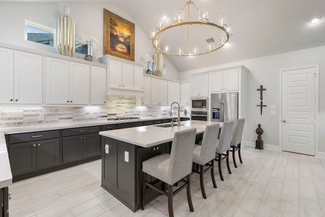 kitchen with a breakfast bar area, a center island with sink, white cabinets, and appliances with stainless steel finishes