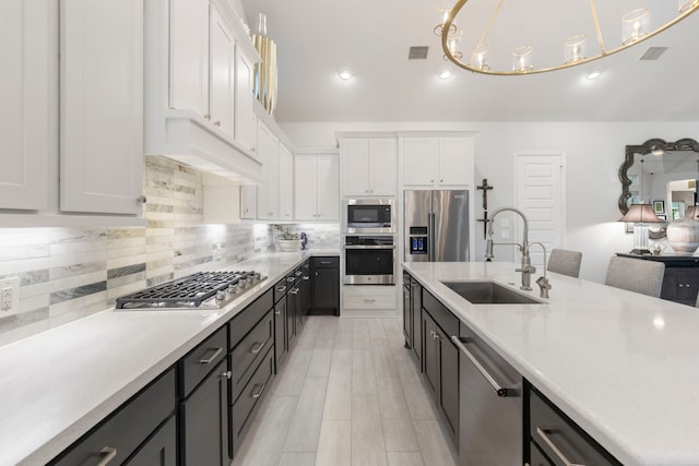 kitchen featuring appliances with stainless steel finishes, sink, pendant lighting, an inviting chandelier, and white cabinets