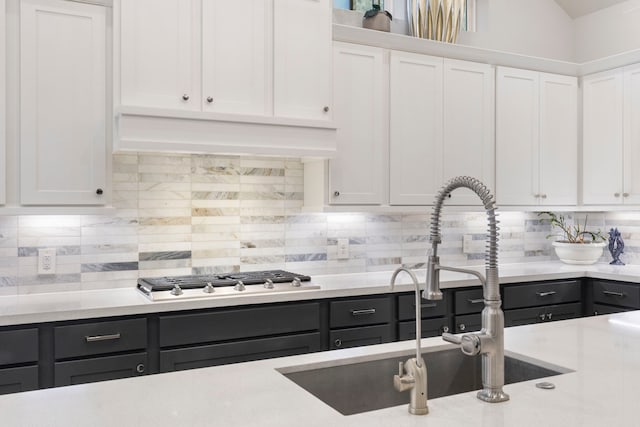 kitchen with white cabinets, stainless steel gas stovetop, and decorative backsplash