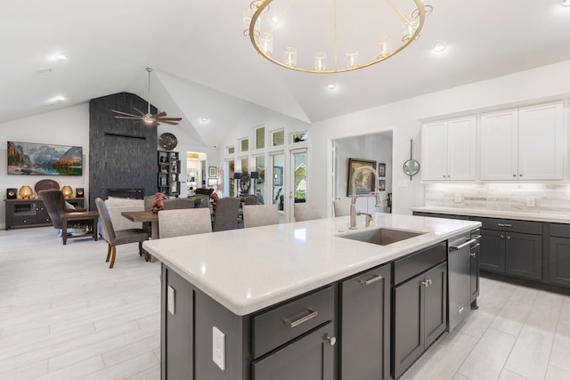 kitchen with backsplash, ceiling fan, sink, a center island with sink, and white cabinets