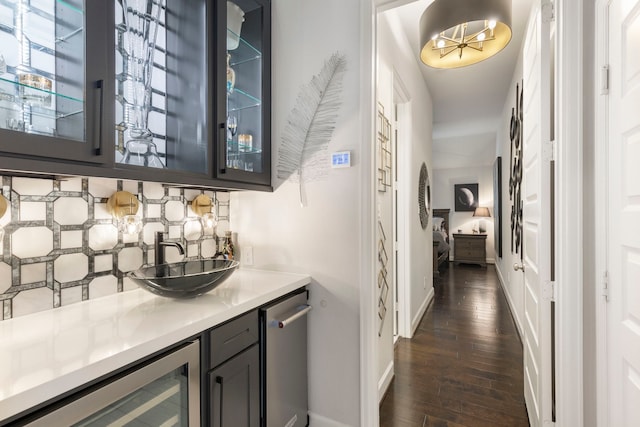 bar featuring dark hardwood / wood-style floors, sink, wine cooler, and tasteful backsplash