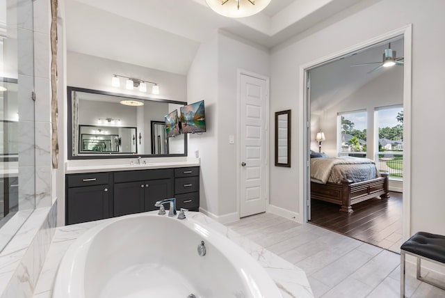 bathroom featuring tiled bath, ceiling fan, vanity, and lofted ceiling