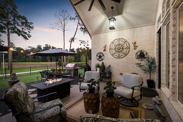 patio terrace at dusk featuring grilling area and an outdoor living space with a fire pit