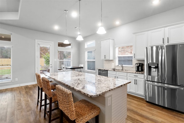 kitchen featuring stainless steel appliances, sink, decorative light fixtures, white cabinetry, and a kitchen island