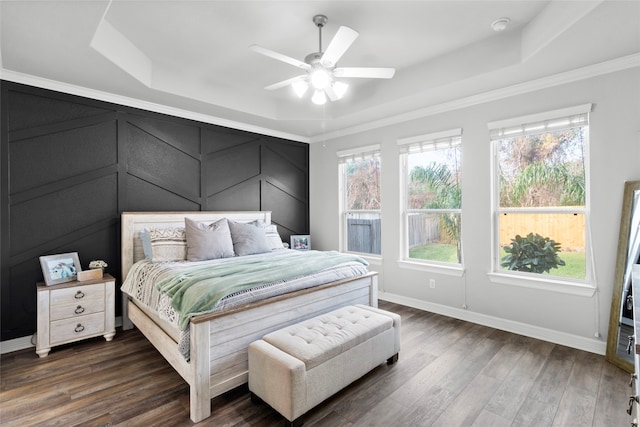 bedroom featuring ceiling fan, a tray ceiling, ornamental molding, and dark hardwood / wood-style floors