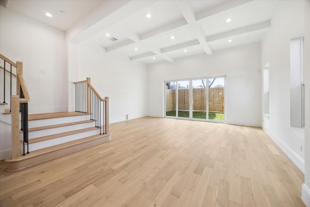 unfurnished living room featuring beam ceiling, light hardwood / wood-style flooring, a towering ceiling, and coffered ceiling