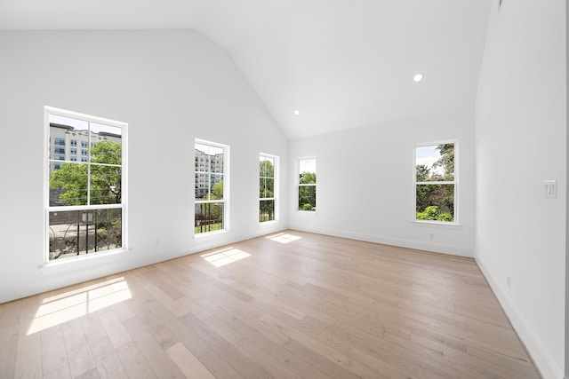 spare room featuring high vaulted ceiling and light hardwood / wood-style flooring