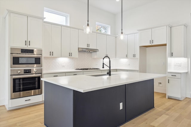 kitchen with pendant lighting, a center island with sink, white cabinetry, and sink