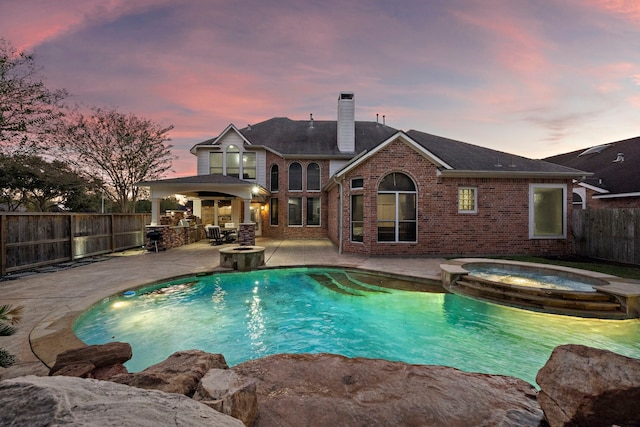 pool at dusk with an in ground hot tub, area for grilling, and a patio area