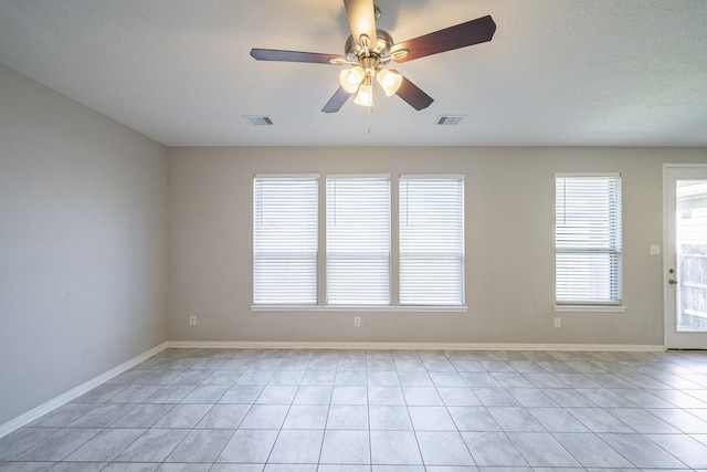 spare room with ceiling fan, a textured ceiling, and light tile patterned floors