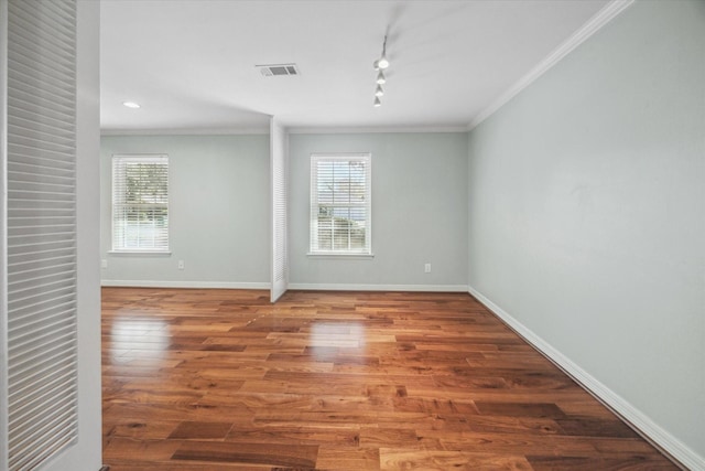 unfurnished room featuring wood-type flooring, track lighting, and ornamental molding