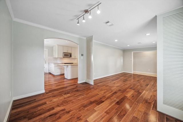 unfurnished living room featuring dark hardwood / wood-style flooring, crown molding, and track lighting