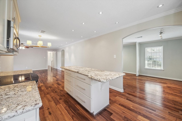 kitchen with dark hardwood / wood-style flooring, ornamental molding, a spacious island, white cabinetry, and hanging light fixtures