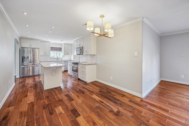 kitchen with a kitchen island, white cabinetry, stainless steel appliances, and hanging light fixtures