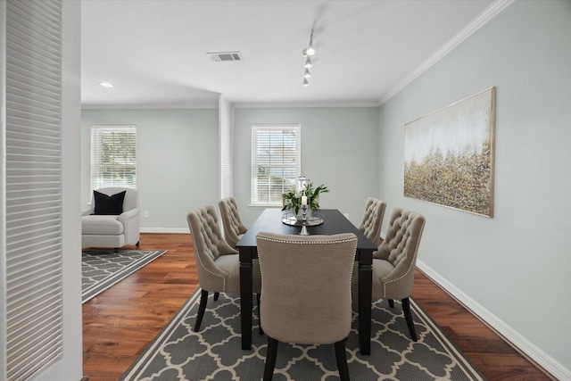 dining area with a wealth of natural light, track lighting, hardwood / wood-style flooring, and crown molding