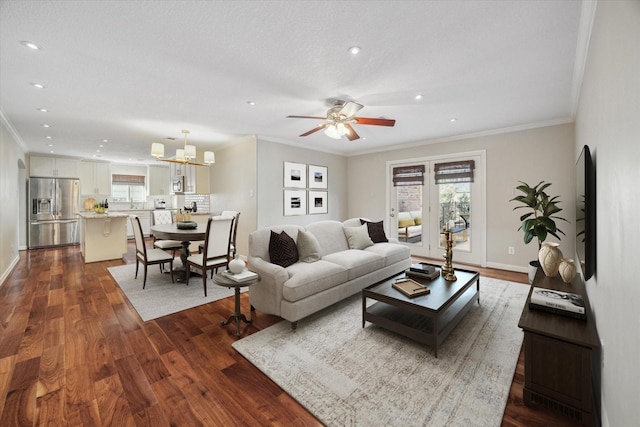 living room featuring dark hardwood / wood-style floors, ornamental molding, and ceiling fan with notable chandelier