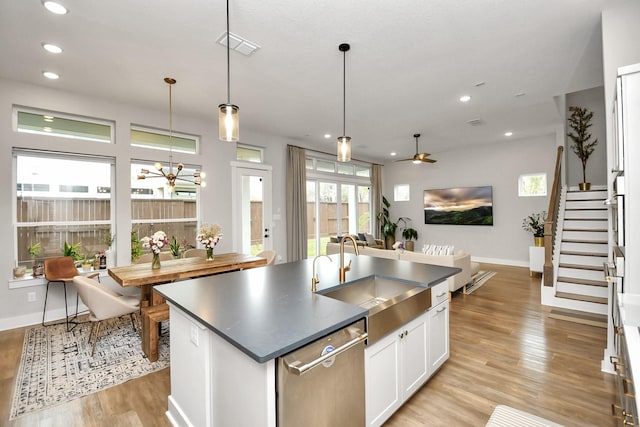 kitchen featuring sink, stainless steel dishwasher, a center island with sink, white cabinets, and ceiling fan with notable chandelier