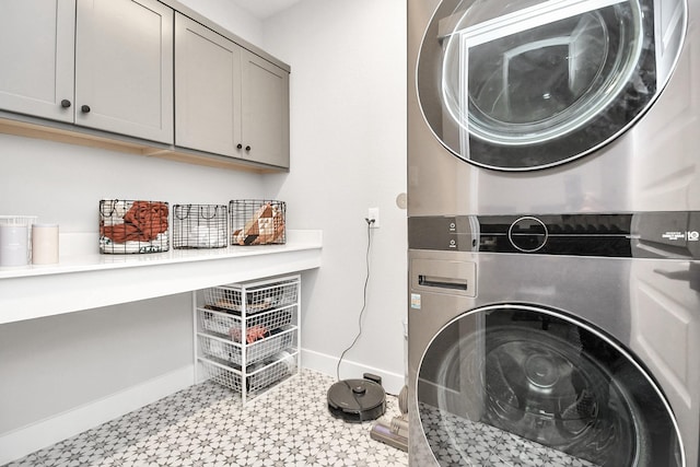 washroom featuring stacked washer / dryer and cabinets