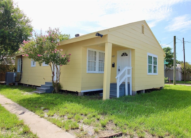 bungalow-style home with central air condition unit and a front yard