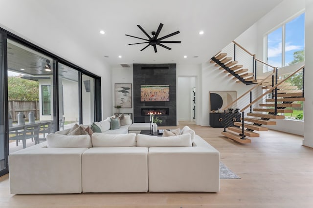 living room featuring a large fireplace, light hardwood / wood-style flooring, and ceiling fan