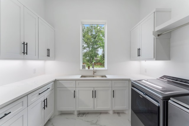 clothes washing area with cabinets, washer and clothes dryer, and sink