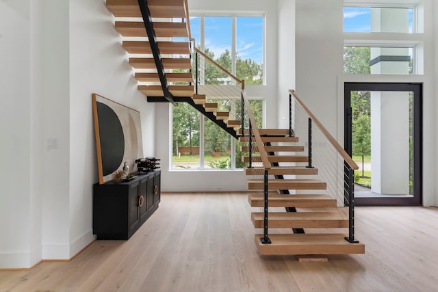 staircase with wood-type flooring and a high ceiling