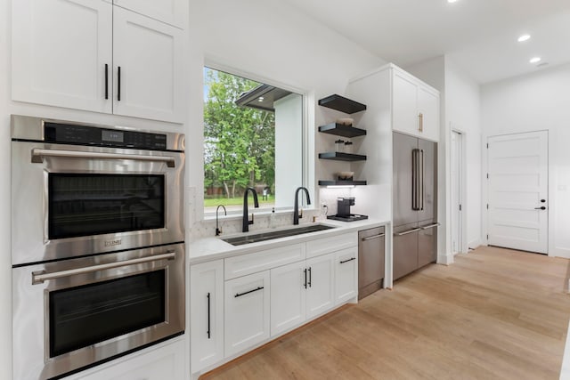 kitchen featuring white cabinets, light hardwood / wood-style floors, sink, and appliances with stainless steel finishes