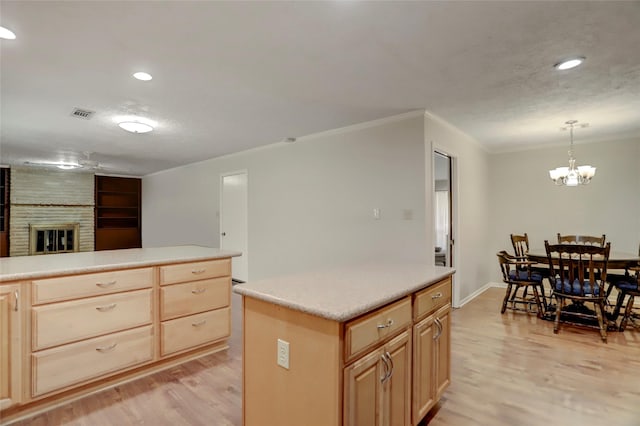 kitchen with a fireplace, a kitchen island, light wood-type flooring, and hanging light fixtures