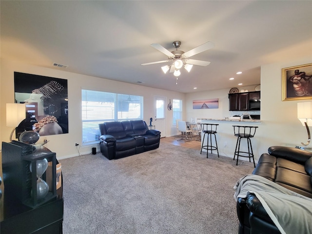 carpeted living room with ceiling fan