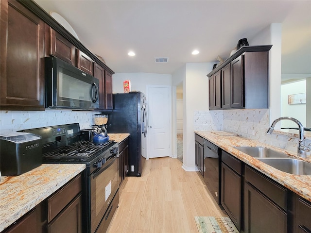 kitchen featuring light stone countertops, light hardwood / wood-style floors, black appliances, backsplash, and sink