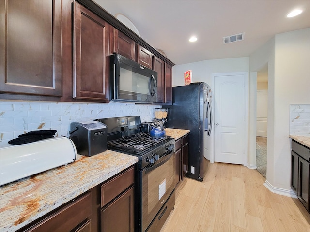 kitchen featuring black appliances, light wood-type flooring, light stone counters, dark brown cabinetry, and tasteful backsplash