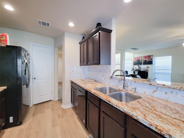 kitchen featuring light stone countertops, sink, light hardwood / wood-style floors, black appliances, and dark brown cabinetry