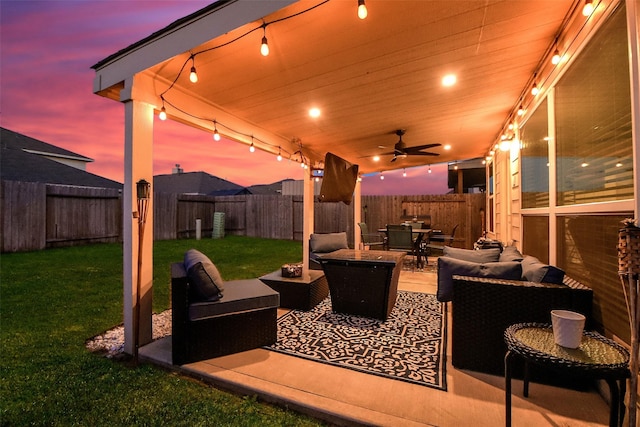 patio terrace at dusk with ceiling fan, a yard, and outdoor lounge area