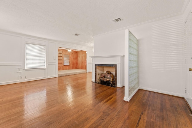 unfurnished living room with hardwood / wood-style floors, a fireplace, crown molding, and a textured ceiling