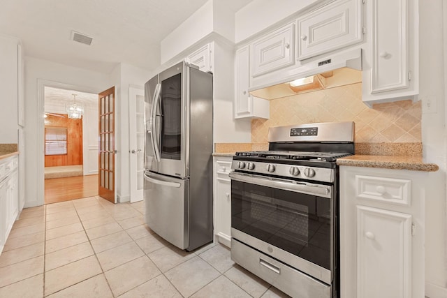 kitchen featuring decorative backsplash, premium range hood, stainless steel appliances, white cabinets, and light tile patterned flooring