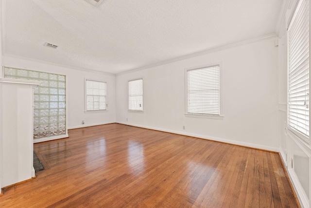 spare room with hardwood / wood-style flooring, a healthy amount of sunlight, crown molding, and a textured ceiling