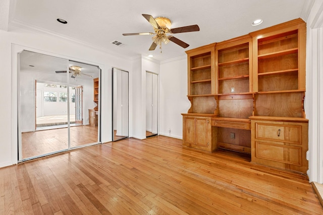 unfurnished living room with ornamental molding, built in desk, and light wood-type flooring