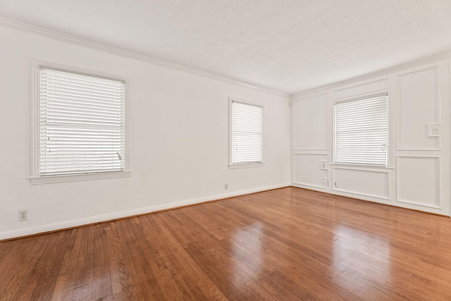 spare room featuring a wealth of natural light, hardwood / wood-style flooring, and ornamental molding