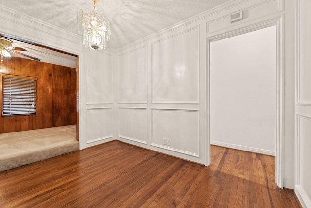 empty room featuring ceiling fan with notable chandelier, wood-type flooring, a textured ceiling, and ornamental molding