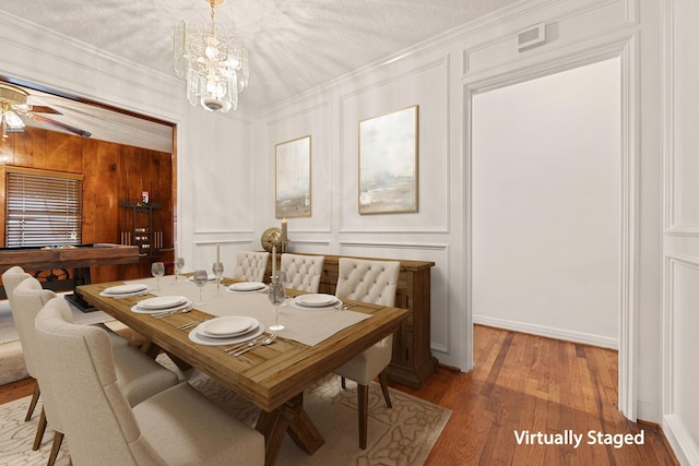 dining area featuring crown molding, ceiling fan with notable chandelier, a textured ceiling, and hardwood / wood-style flooring