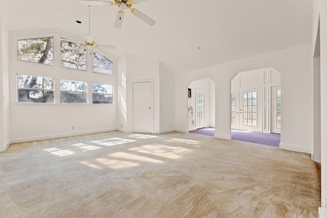 unfurnished living room with ceiling fan, high vaulted ceiling, and light colored carpet