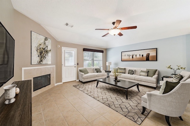 living room featuring ceiling fan, a fireplace, light tile patterned flooring, and a textured ceiling