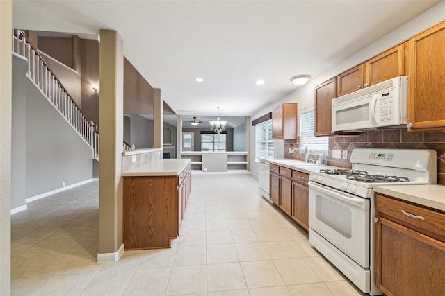 kitchen with white appliances, hanging light fixtures, light tile patterned floors, tasteful backsplash, and a chandelier