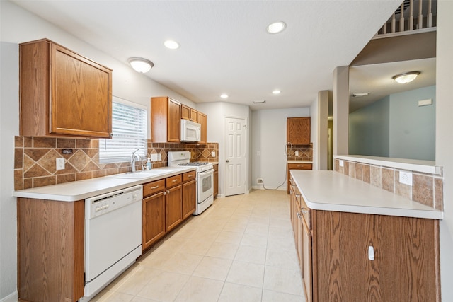 kitchen featuring backsplash, light tile patterned flooring, white appliances, and sink